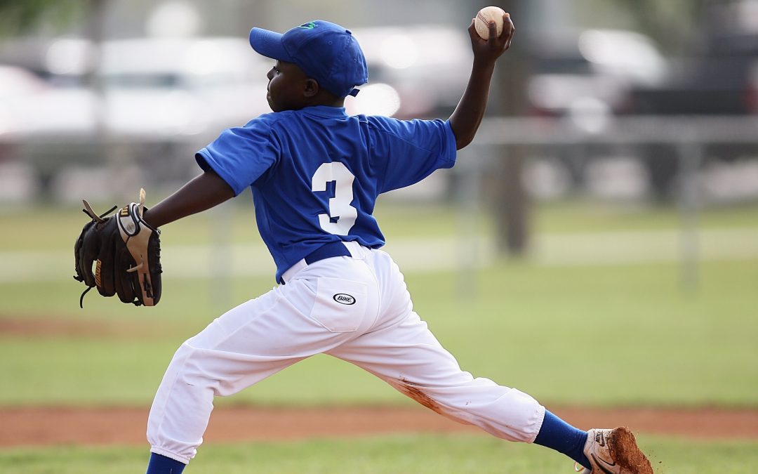 Young baseball player in uniform throws from pitcher's mound, illustrating charitable planning.