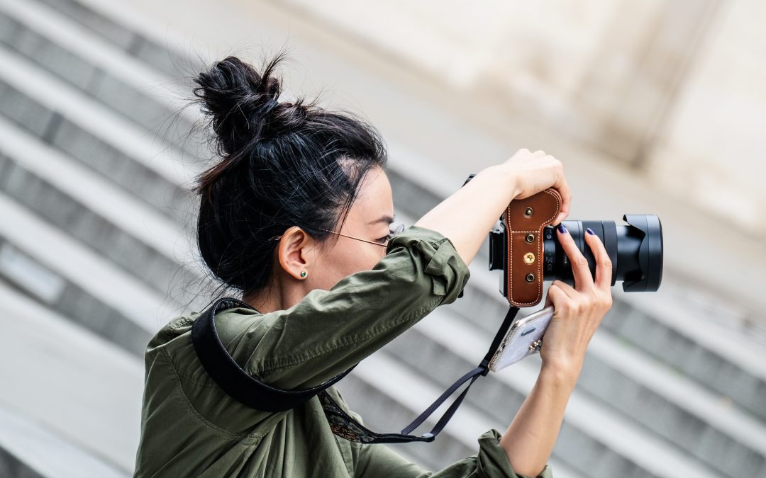 Woman takes a photo. To illustrate photography as a side hustle option to eliminate debt.