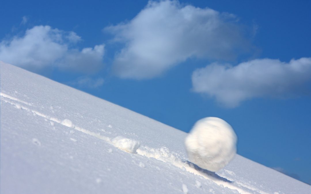 A large snowball rolls downhill. Represents the snowball vs. avalanche methods of debt reduction.