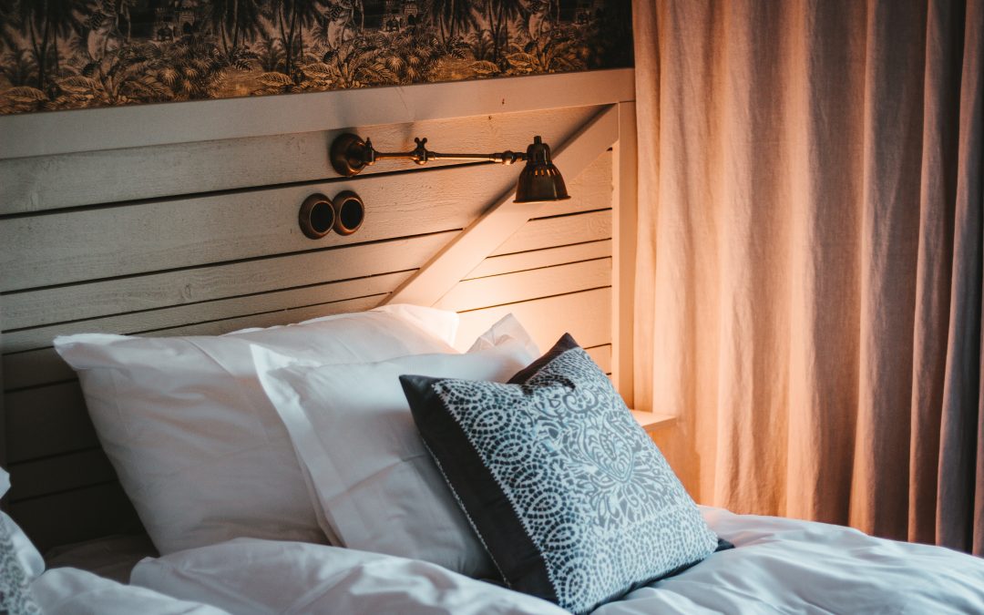 A bed with pillows and a reading lamp: Illustrates guide on how to start an Airbnb