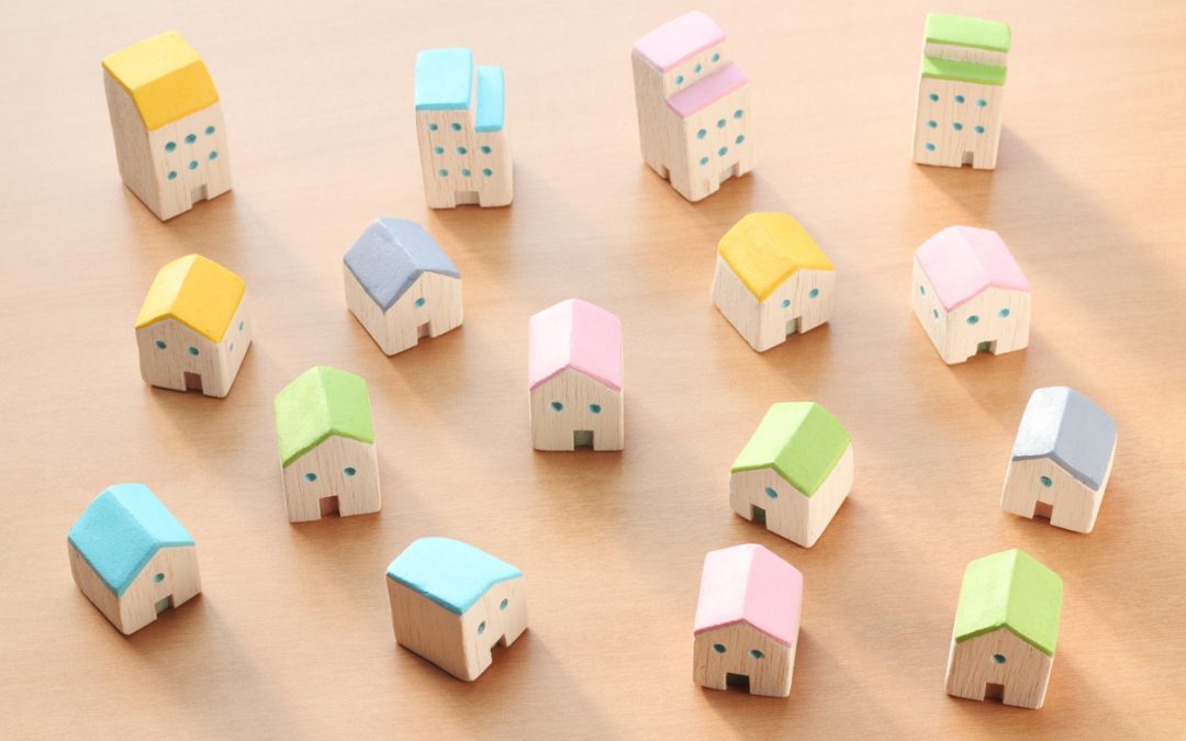 Miniature wooden houses and apartments, likely from children's toy set. Illustrates article on HUD Housing Choice Voucher (HCV) program.