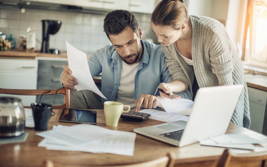 Couple looks over papers in a kitchen, which illustrates a personal financial planning process.
