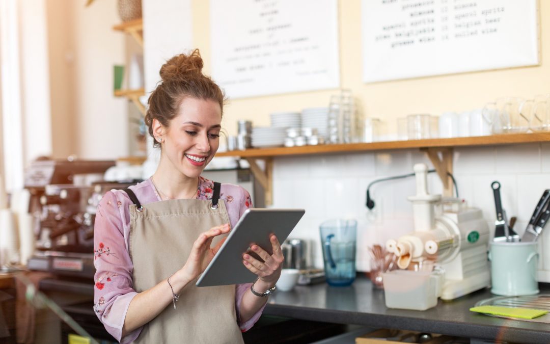 Young woman using digital tablet in coffee shop: Illustrates story on buying a franchise