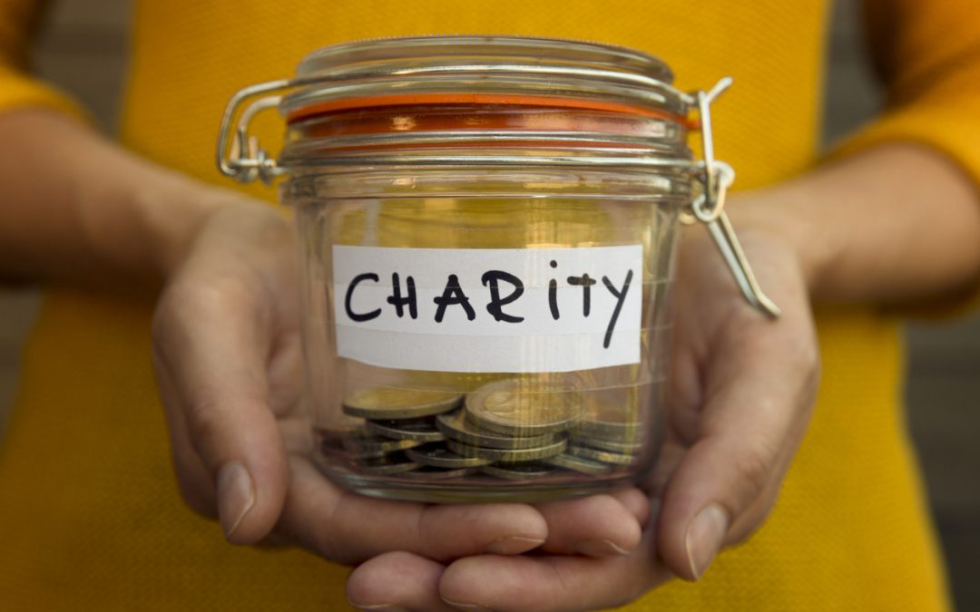 Person collecting money for charity holds jar with coins. To illustrate ways to give back.